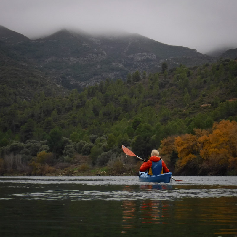 noia en piragua per l'Ebre amb les muntanyes dels voltants tapades de boira