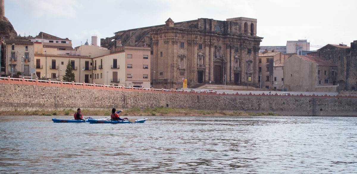 Dos persones navegant en caiac per davant la catedral de tortosa